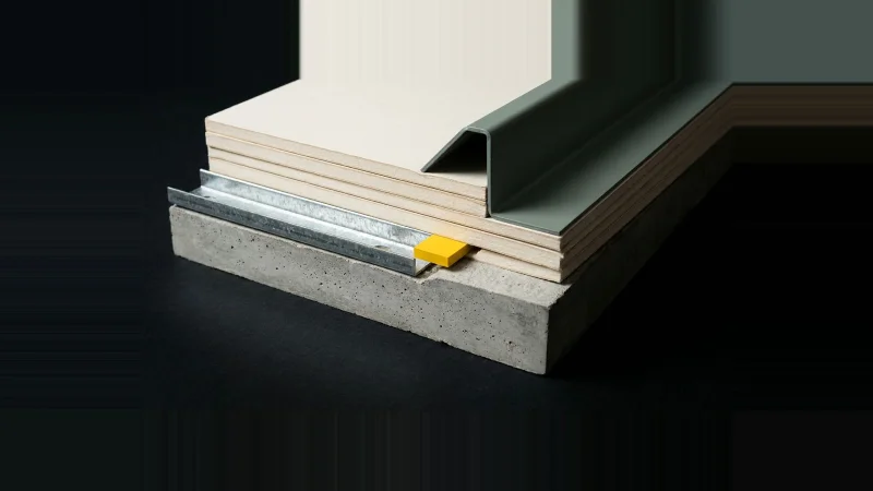 Close low-angle view of a wall-to-slab cross-section, with a yellow shim set into the open joint gap.