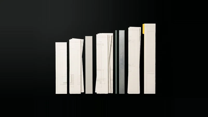 Overhead view of trimmed specification paper strips arranged as an ascending bar chart on black, one tagged yellow.