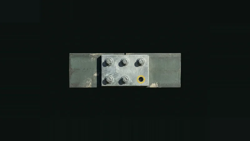 Overhead view of a galvanised steel splice plate with bolts seated except one empty hole ringed in yellow
