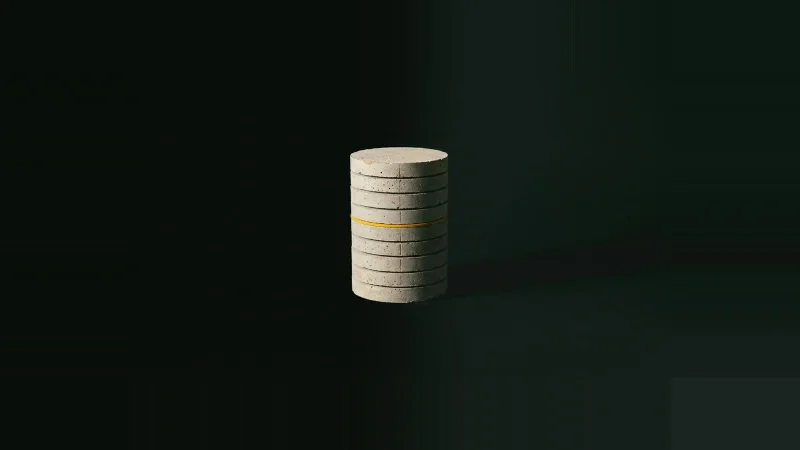 Small pale concrete core cylinder sliced into stacked discs on black, one thin seam picked out in yellow