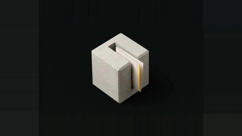 Pale concrete specimen block with a milled slot holding a folded off-white spec sheet edged in yellow, on black.