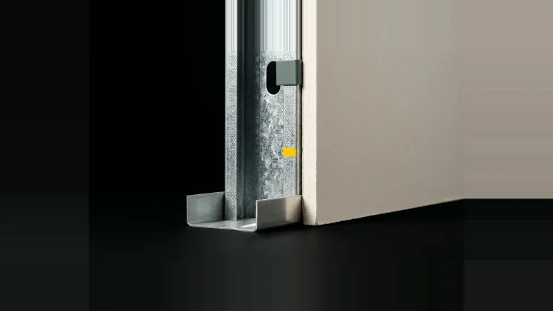 Close low-angle view of a galvanised C-H shaft wall stud receiving a pale gypsum liner panel against black