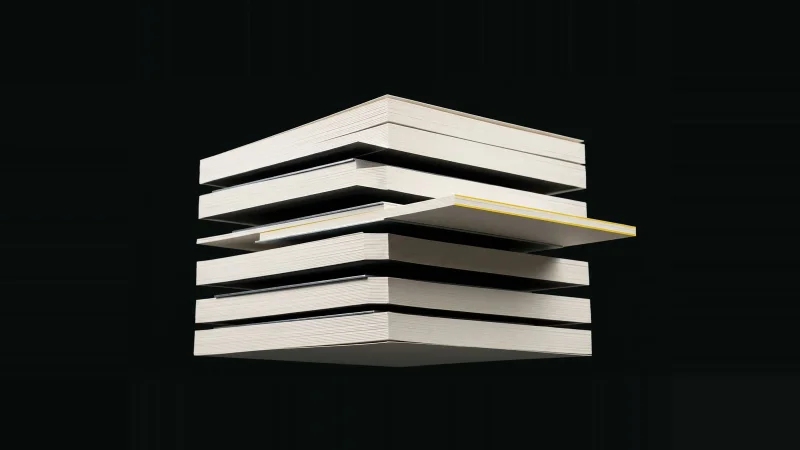 A thick block of blank off-white paper sliced and exploded into layers, one sheet slid out and edge-lit yellow.