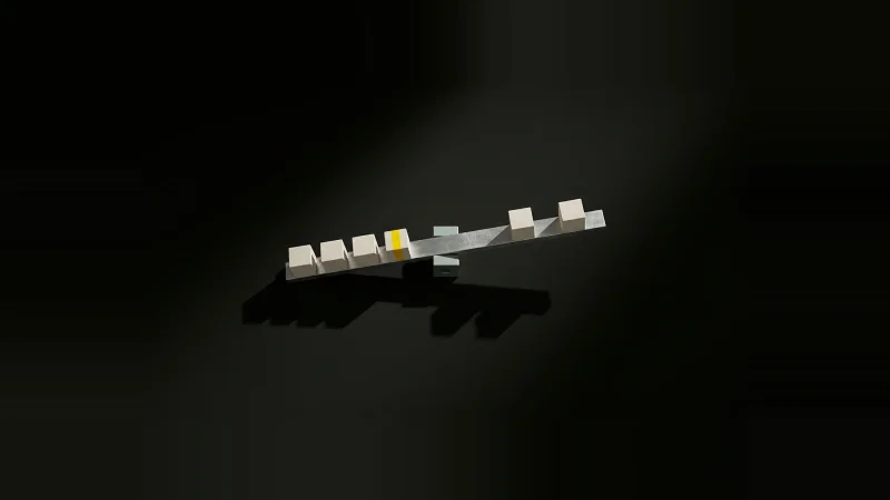 Overhead view of a steel beam on a fulcrum loaded with six concrete cubes, one marked yellow, in darkness