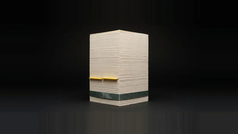 A thick upright slab of off-white specification paper on black, with a single yellow index tab deep inside the stack.