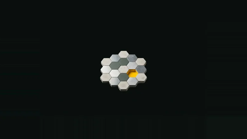 Small mosaic of concrete and metal tiles in darkness with one tile missing, its socket lined in yellow