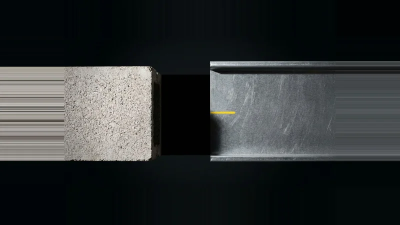 Overhead close-up of galvanised flashing stopping short of a concrete block edge, leaving a black unclosed gap between them.
