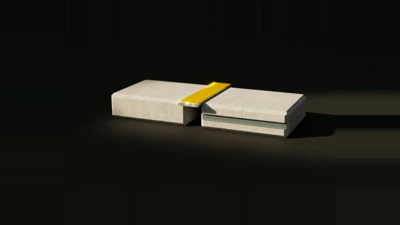 Two pale concrete slabs with a narrow gap between them, bridged by a small yellow metal shim