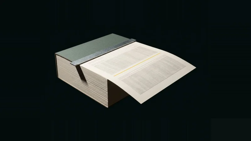 A single specification page drawn out from deep inside a thick paper stack, marked with one yellow line, on black.