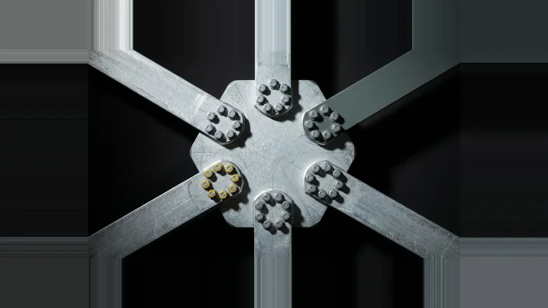 Overhead view of a galvanised steel gusset plate with six bolted members radiating out, one bolt ring painted yellow.