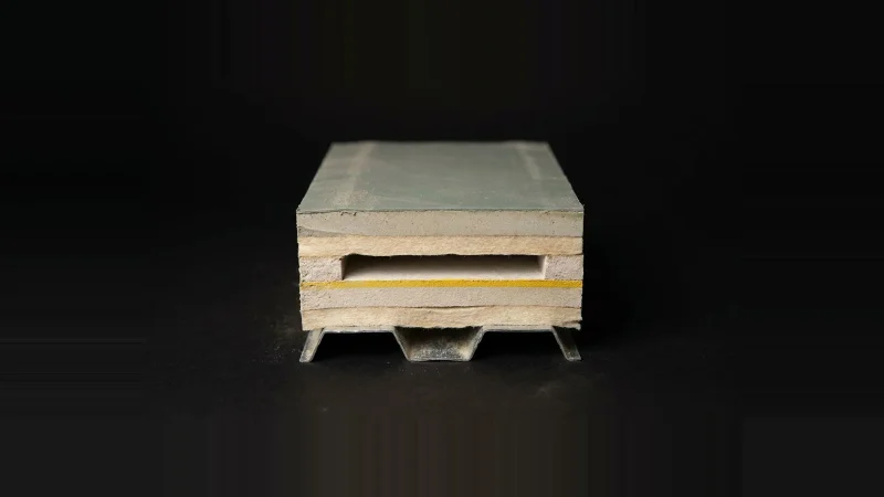 Cross-section specimen of a layered roof assembly with one interior layer missing, marked by a yellow stripe