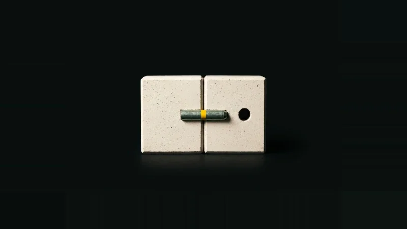 Two pale concrete blocks joined by a yellow-banded steel dowel beside an identical joint with an empty dowel hole.